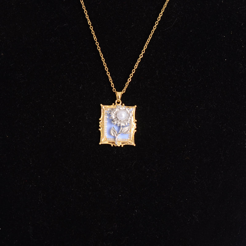 سلسلة رفيعة بدلاية شكل برواز مربع بداخله وردة بارزة لون ذهبي